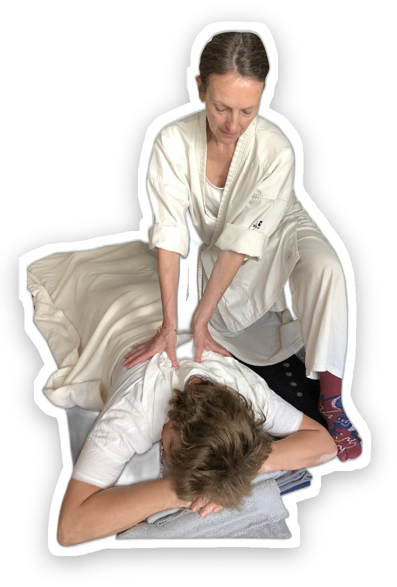 Marie Scheibli en séance de shiatsu, agenouillée derrière une personne allongée sur un futon